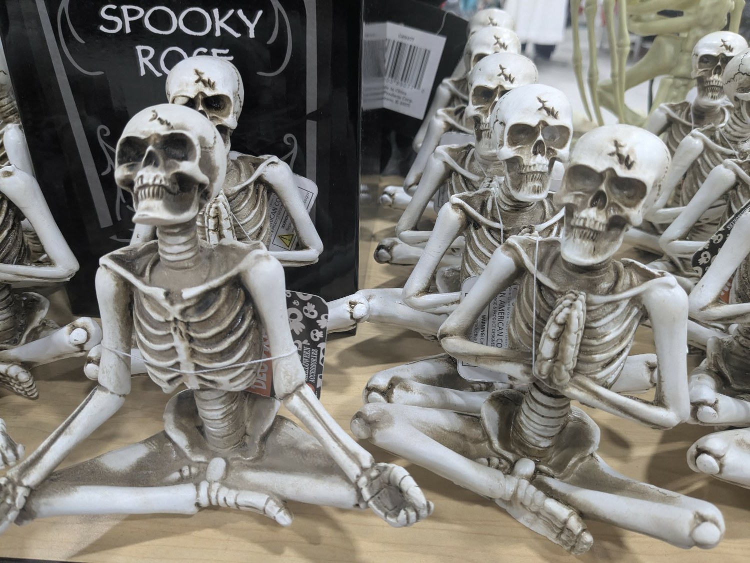 Skeleton figurines on a shelf beside a Spooky Rose Halloween display