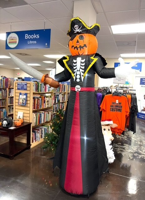 Inflatable pumpkin-head pirate decoration in a Goodwill store book aisle