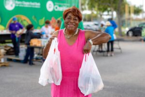 Mary Brown smiling with two bags of groceries at a Harry Chapin Food Bank distribution