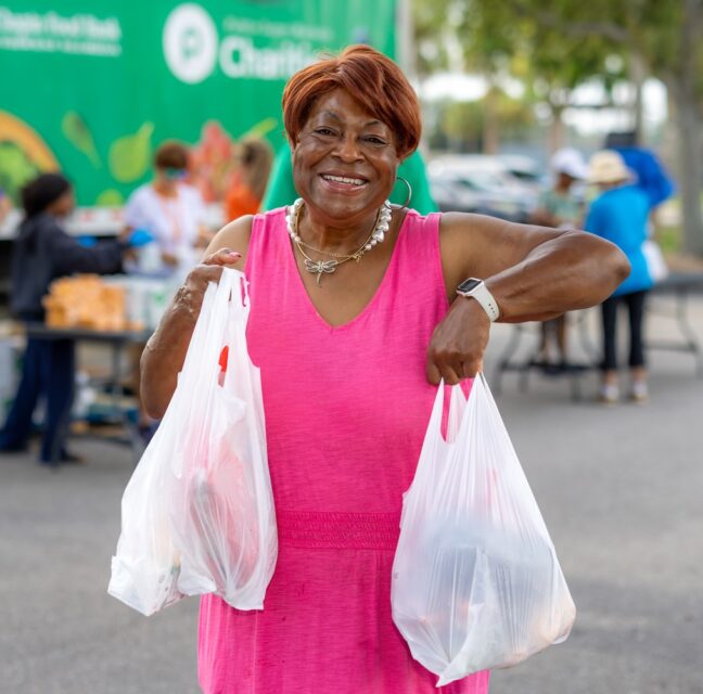 Mary Brown smiling with two bags of groceries at a Harry Chapin Food Bank distribution