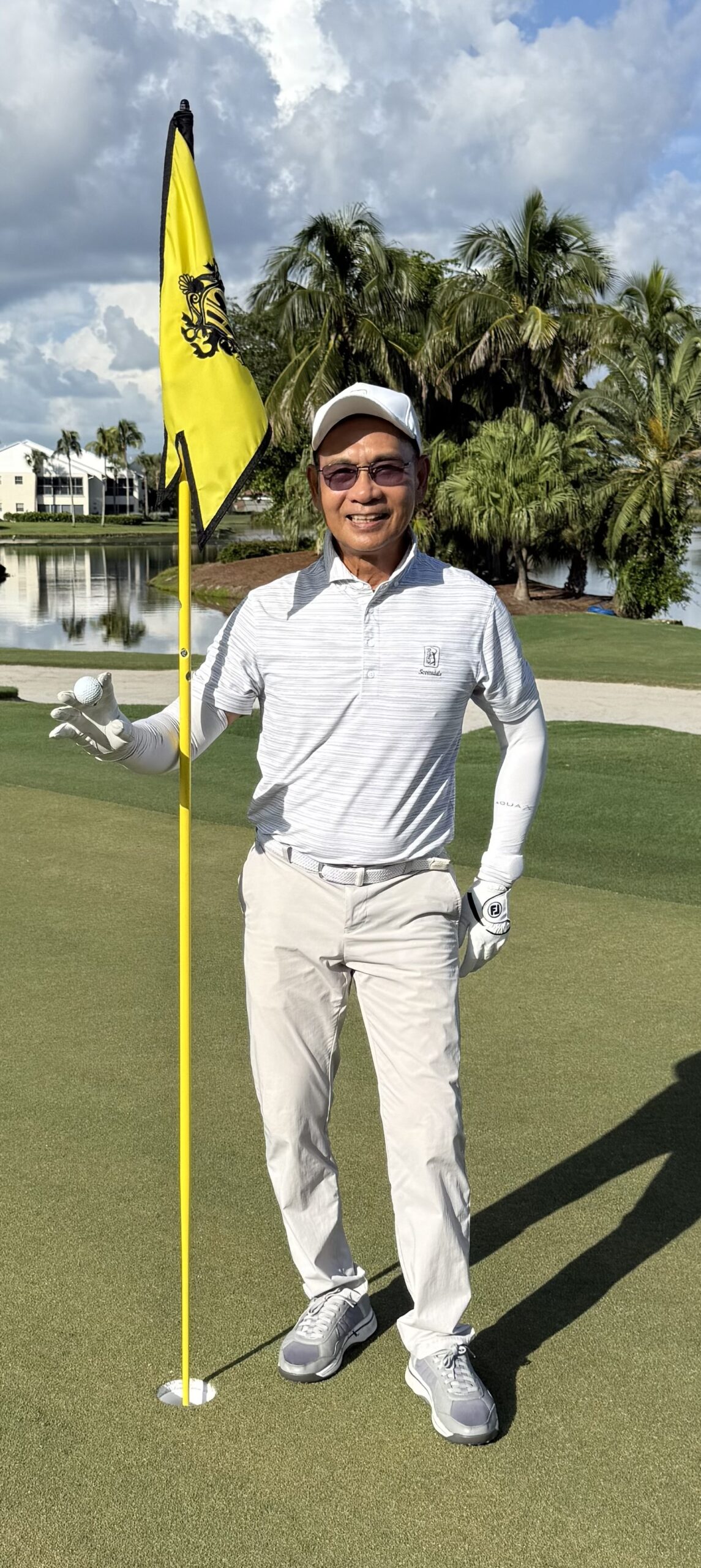 Wen Wu on the ninth green holding the flagstick and his ball after a hole-in-one