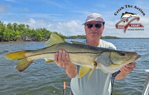 Angler holding a large snook aboard a Gulf Coast Guide Service charter boat